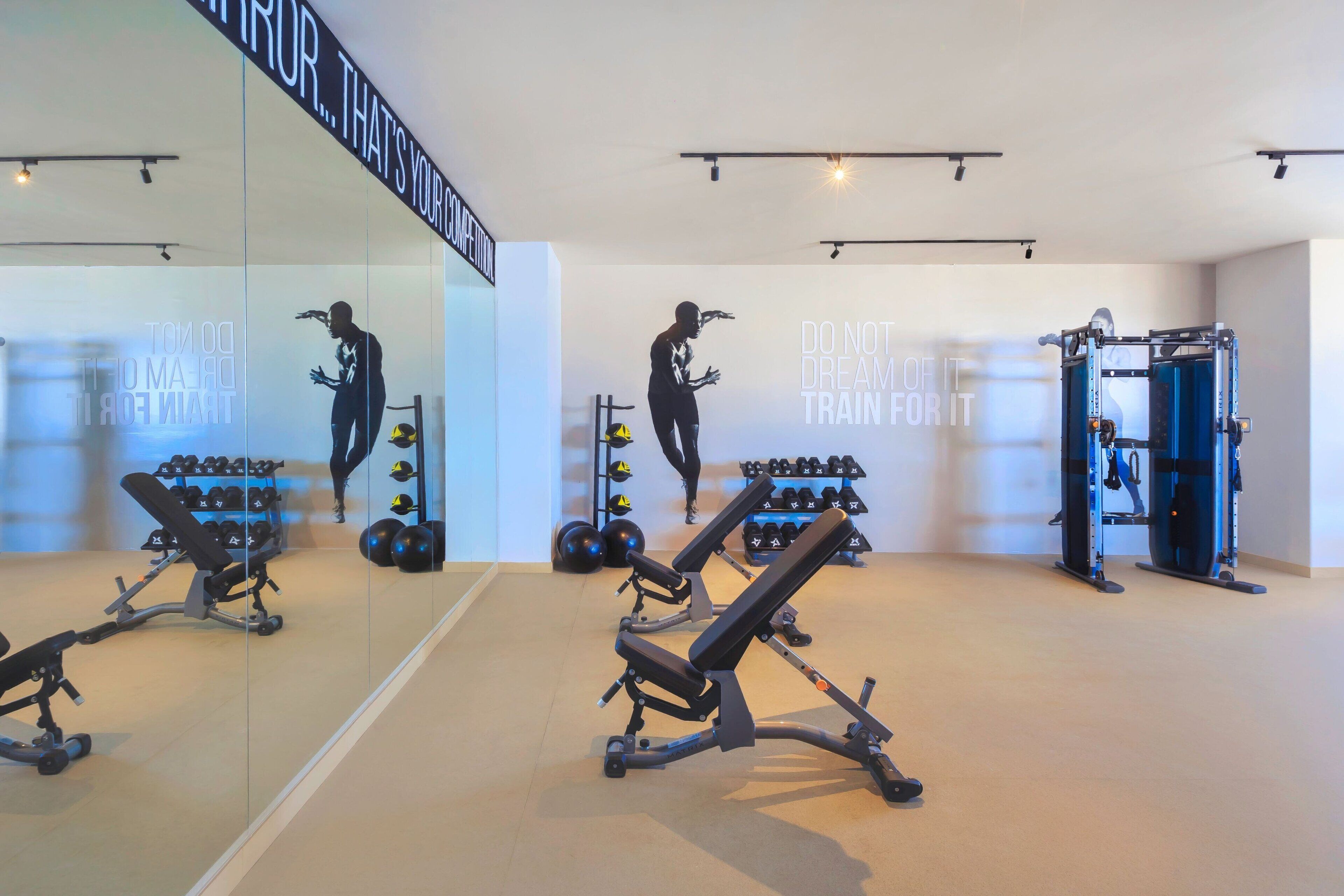 A modern gym with exercise equipment, a mirror, and motivational wall art.