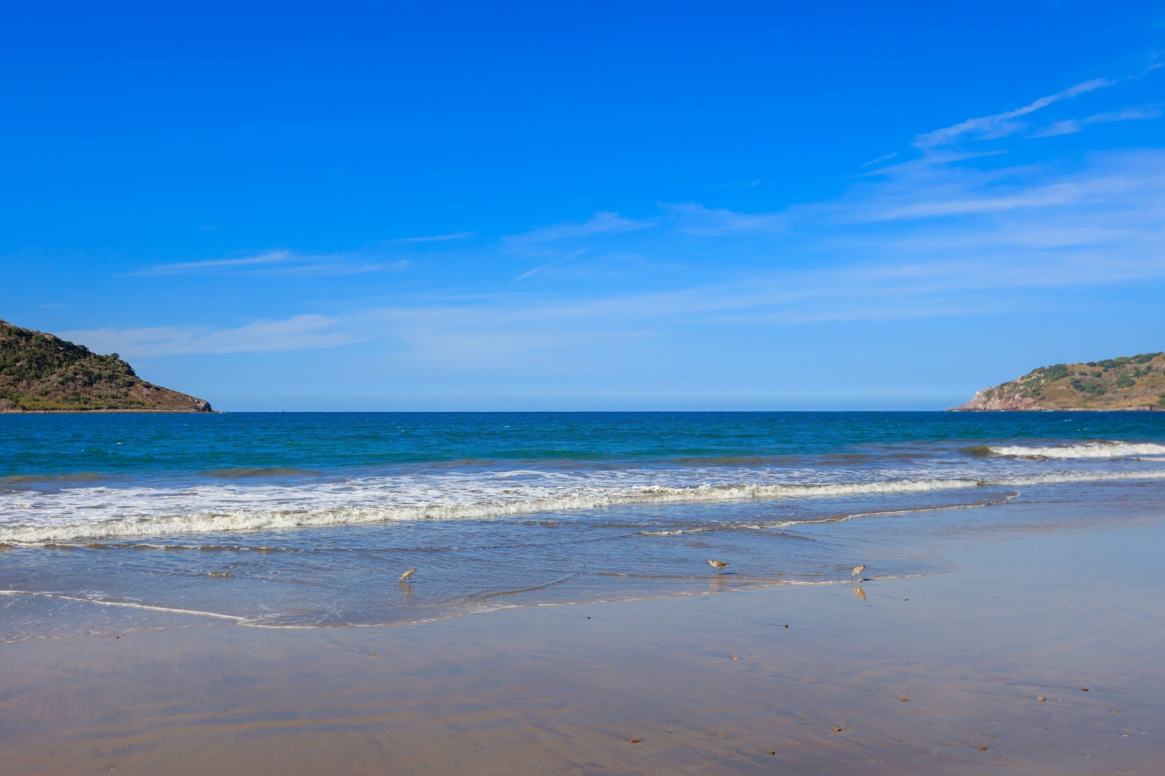Een strand met helderblauw water en een zandstrand.