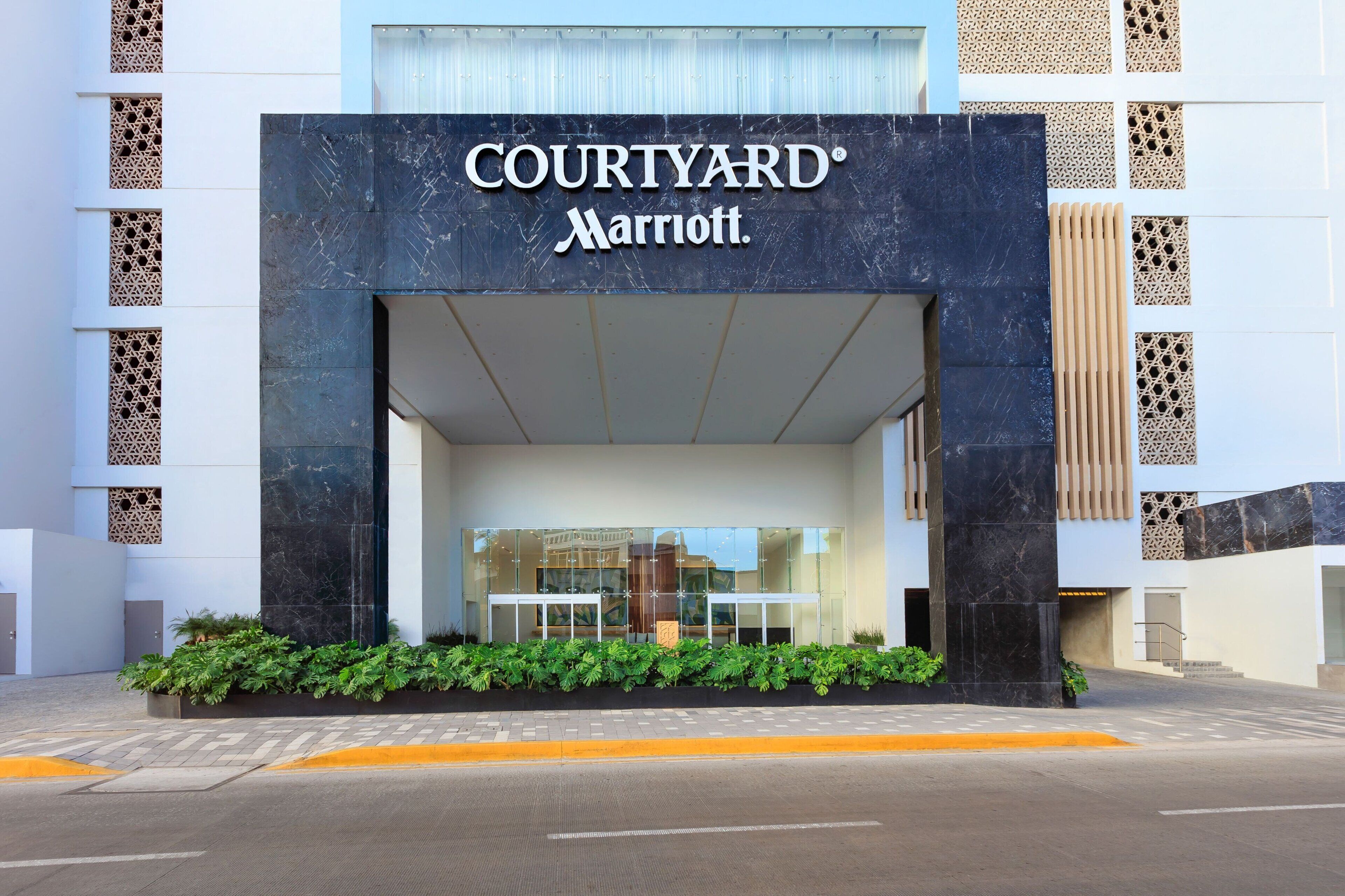 L’entrée de l’hôtel Courtyard Marriott se distingue par sa façade moderne, ses grandes fenêtres en verre et son espace d ’entrée aménagé.