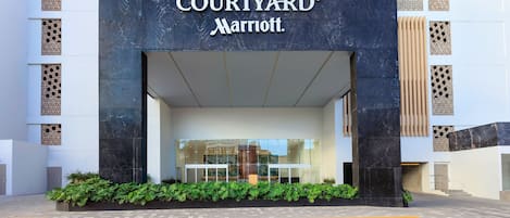The Courtyard Marriott hotel entrance with a modern facade, large glass windows, and a landscaped entrance area.