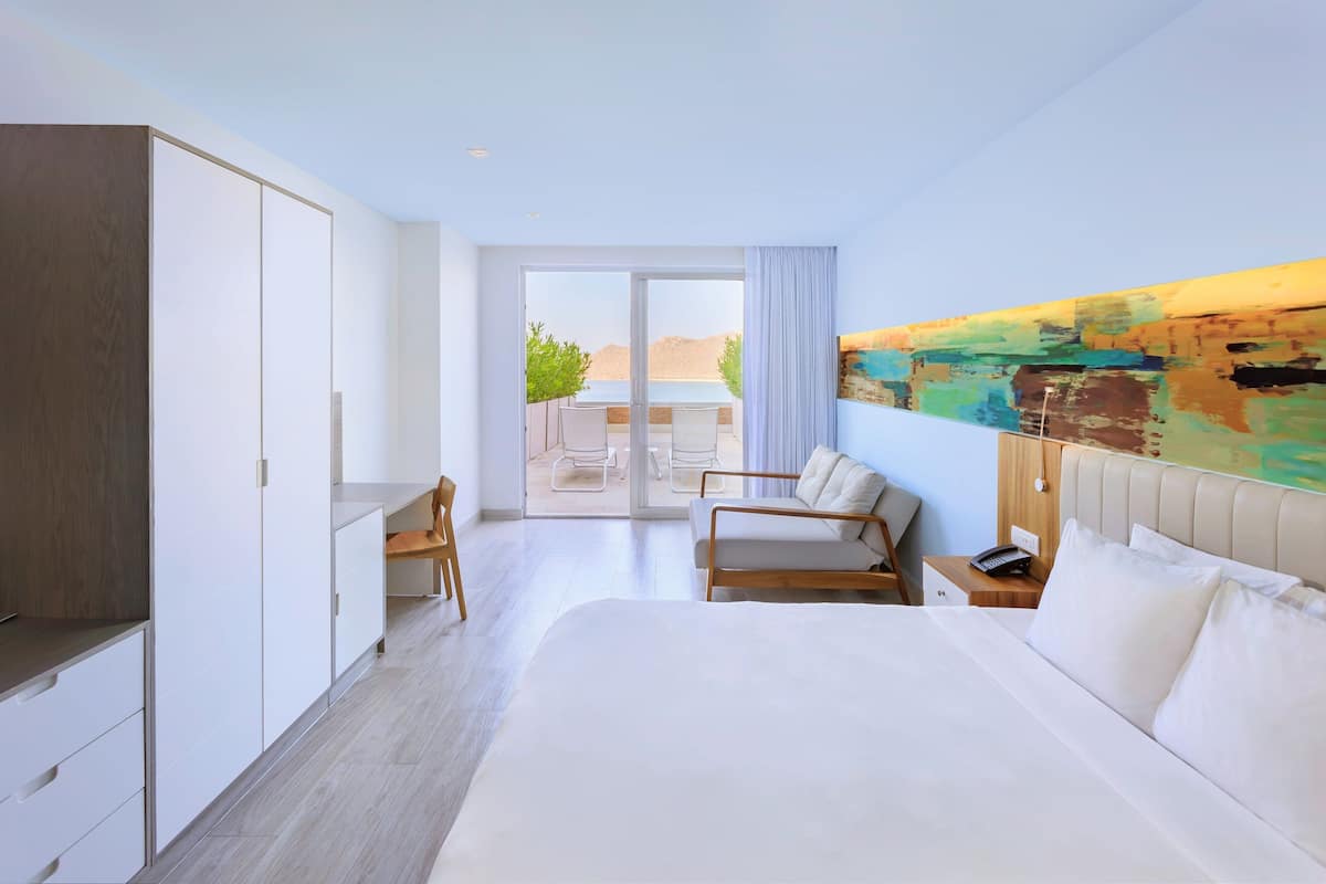Ein modernes Hotelzimmer mit einem großen Bett, einem Schreibtisch und Blick ins Freie.