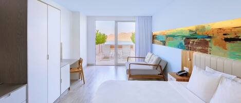 A modern hotel room with a large bed, a desk, and a view of the outdoors.