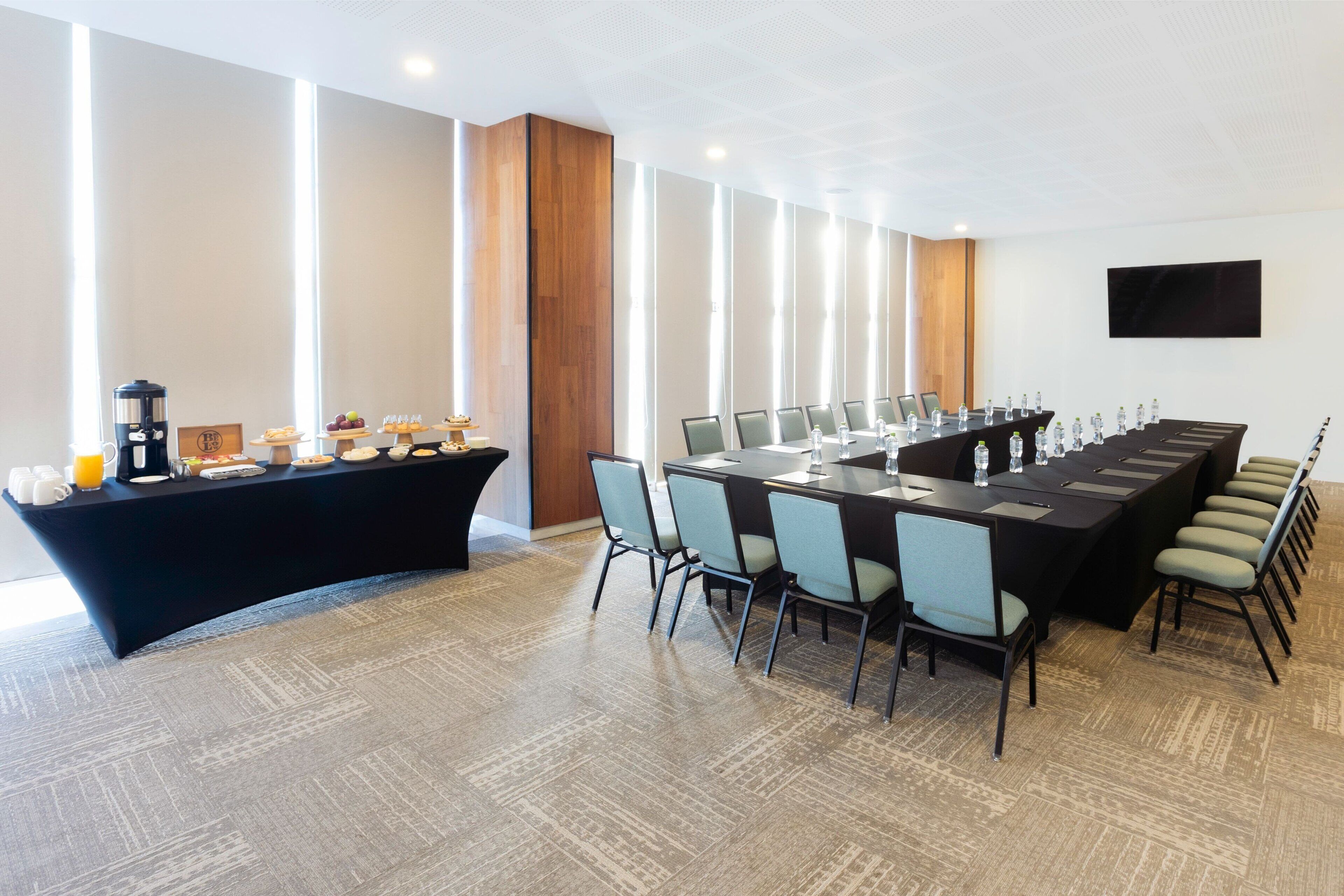 A conference room with a long table, chairs, and a buffet table with food and drinks.