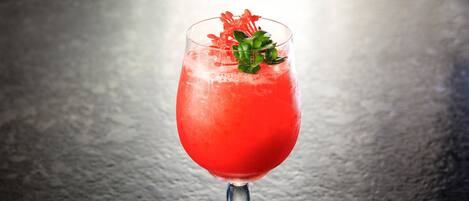 A cocktail glass with a red drink, a green garnish, and a metal stem.