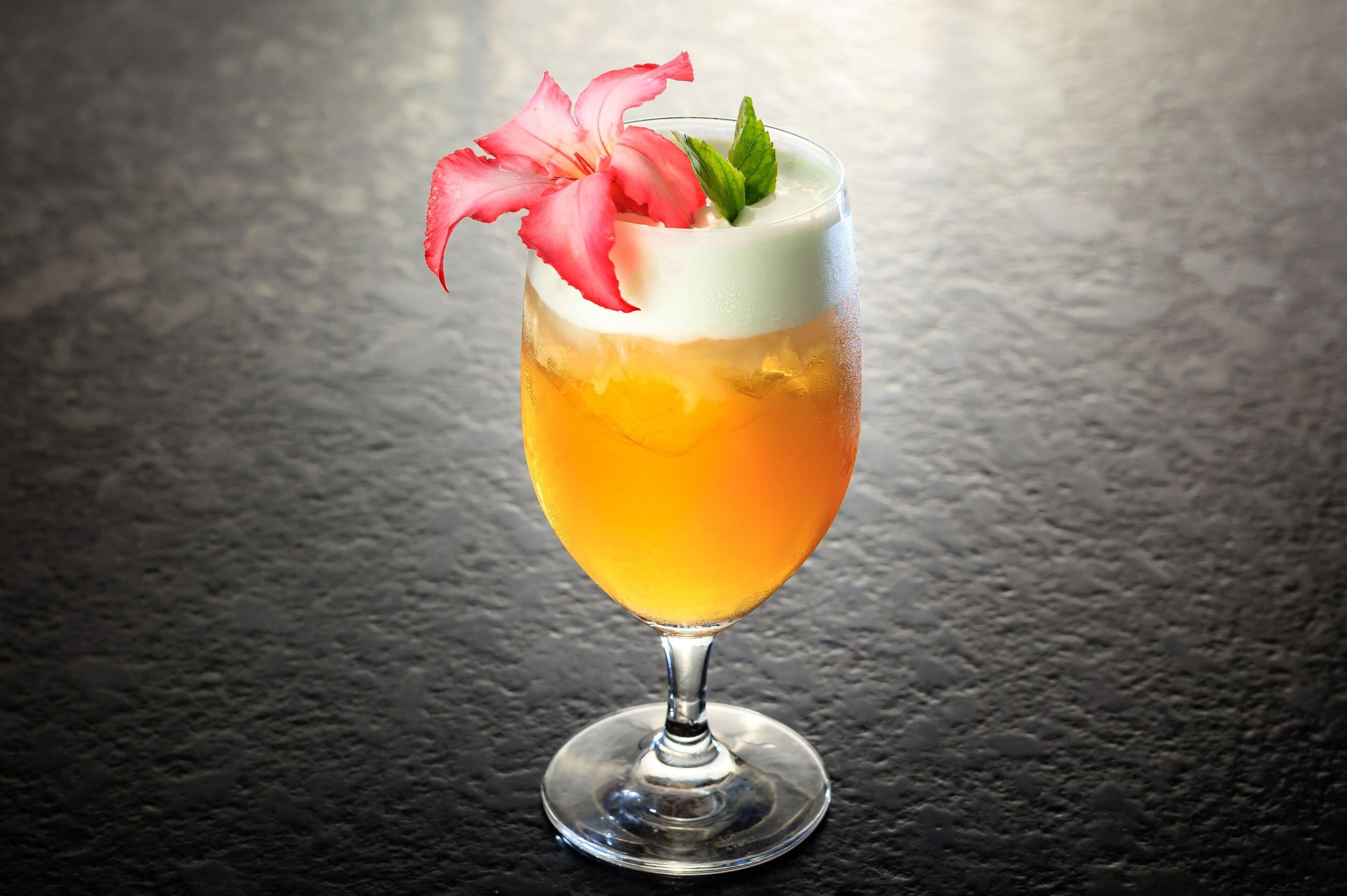 A cocktail in a stemmed glass with a flower garnish.