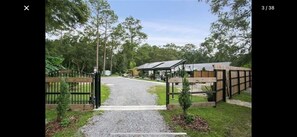 A gated entrance to a property with a gravel path leading to a building with a sloped roof. - BARNDOMINIUM ONE OF A KIND!!! (Mandeville)