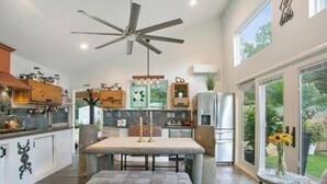 Une cuisine moderne avec un coin repas, de grandes fenêtres et un ventilateur de plafond.