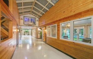 A corridor with wooden walls and large windows, leading to a room with a view. - BARNDOMINIUM ONE OF A KIND!!! (Mandeville)