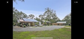 A property with a covered patio, a solar panel, and a large open area with trees.