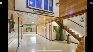 A spacious hallway with wooden flooring, a staircase, and a large window at the end. - BARNDOMINIUM ONE OF A KIND!!! (Mandeville)