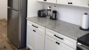 A kitchen with white cabinets, a stainless steel refrigerator, a toaster, a coffee maker, and a dishwasher. - The White House - Silverton Suite A Downstairs (Silverton)