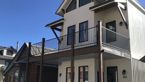 A two-story building with a balcony, a garage door, and a visible address number. - The White House - Silverton Suite A Downstairs (Silverton)