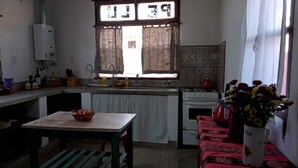 A kitchen with a window, a sink, a stove, and a table with a basket. - Casa Luciérnaga, ideal to enjoy the north of Argentina (humahuaca)