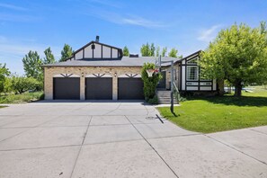 A residential house with a garage, a covered driveway, and a well-maintained lawn.