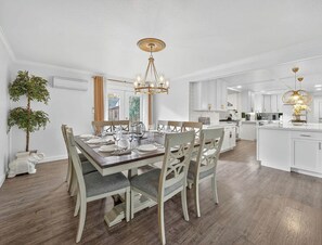 A modern kitchen with white cabinetry, a central island, and a dining area with a wooden table and chairs.