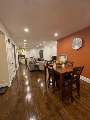 A spacious living area with a dining table, wooden chairs, and a fruit bowl. - Woodlawn Oasis...10 Minutes to Dining & Downtown (Chicago)