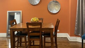 Un coin repas avec une table et des chaises en bois, deux assiettes décoratives accrochées au mur et un miroir.