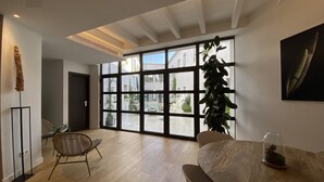 A spacious room with a large window, a dining table, a chair, and a potted plant. - Alaró Natura Rural Suites (Alaro)