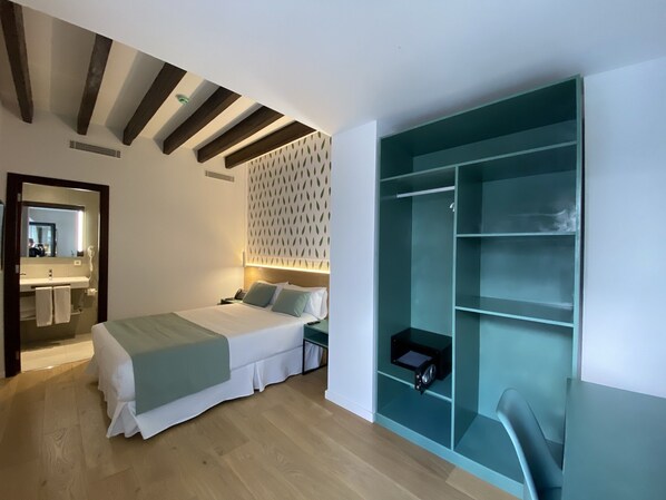 A modern hotel room with a bed, bedside table, and a built-in wardrobe.