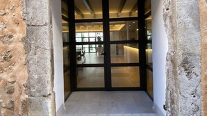 A stone archway leading into a modern interior space with a glass door and a small step. - Alaró Natura Rural Suites (Alaro)