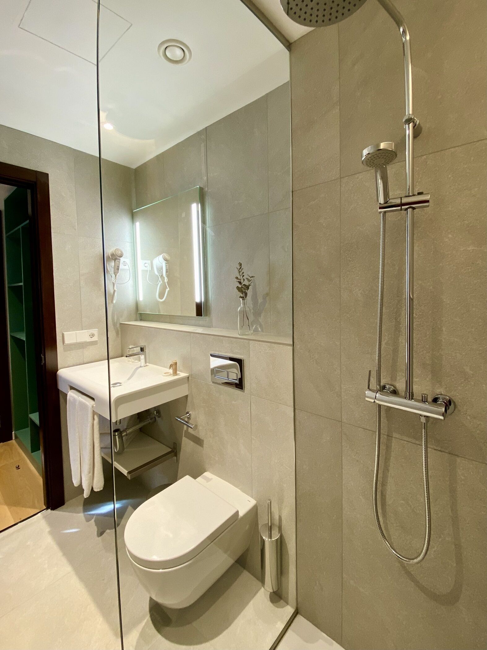 A modern bathroom with a glass-enclosed shower, a white toilet, and a vanity with a mirror.