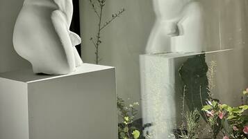 A sculpture of a seated figure with a plant beside it.