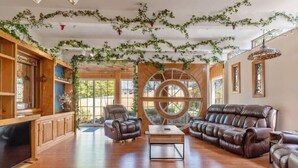 A spacious living room with a large wooden-framed window, leather sofas, and a coffee table.