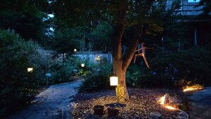 A garden with a tree, a pathway, and a small fire.