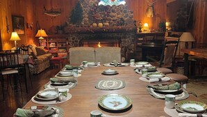 A long dining table set for a meal with a stone fireplace in the background.