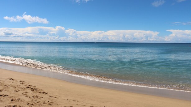 A beach with clear blue water and a sandy shore. - Beach Front (Rincón)