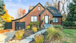 A brick house with a dark roof, a front door, and a garage.