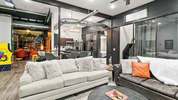 A modern living room with a sofa, coffee table, and a dining area with chairs and a table.