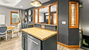 A modern kitchen with a wooden countertop, black cabinetry, and a large mirror.