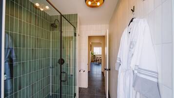 Un baño moderno con cabina de ducha de vidrio, ducha a ras de suelo y un perchero con batas.