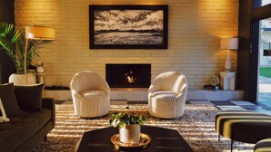 A living room with a fireplace, two armchairs, a sofa, and a coffee table with a plant. - Azure Sky Hotel - Adults Only - A Town & Desert Boutique Hotel (Palm Springs)
