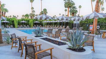 A poolside area with lounge chairs, umbrellas, and a pool.