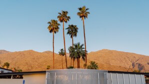 A parking area with a white fence, palm trees, and a mountain in the background. - Azure Sky Hotel - Adults Only - A Town & Desert Boutique Hotel (Palm Springs)