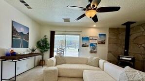 A cozy living room with a sectional sofa, a coffee table, and a fireplace. - Epic Views, Huge House, Acres of J-Trees to explore + Hot Tub, Pool, AC & Golf! (Joshua Tree)