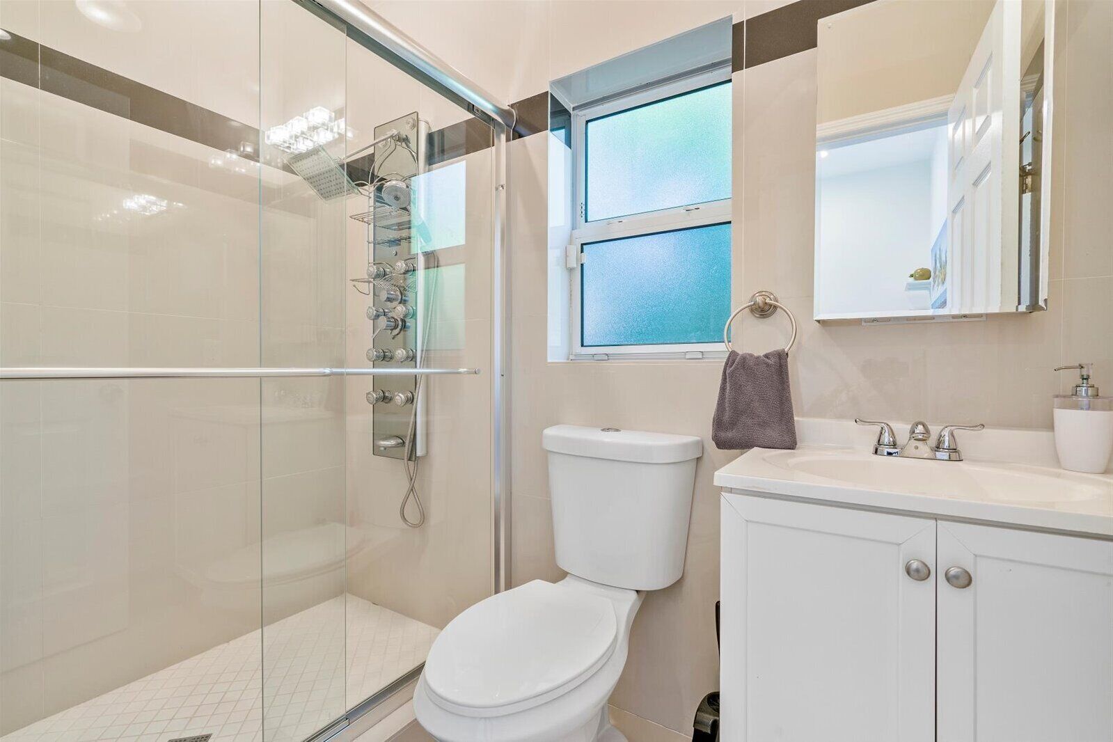 A modern bathroom with a glass-enclosed shower, a white toilet, and a sink with a mirror above it.