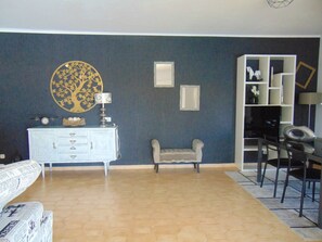 A living room with a blue wall, a white cabinet, a round table, and a chair.