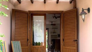 Eine Holztür mit Milchglasfenster, ein gestreifter Stuhl und ein Deckenventilator im Hintergrund.