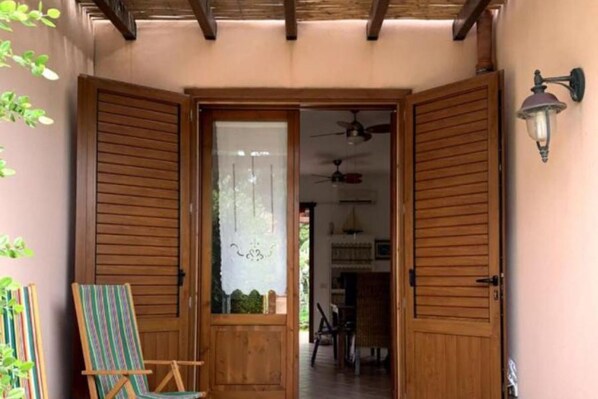 A wooden door with a frosted glass panel, a striped chair, and a ceiling fan in the background.