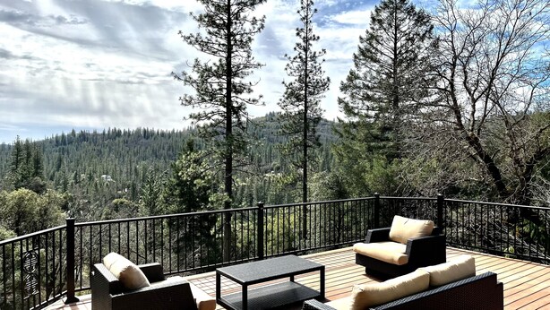 Eine Terrasse mit Korbmöbeln und Blick auf einen Wald.