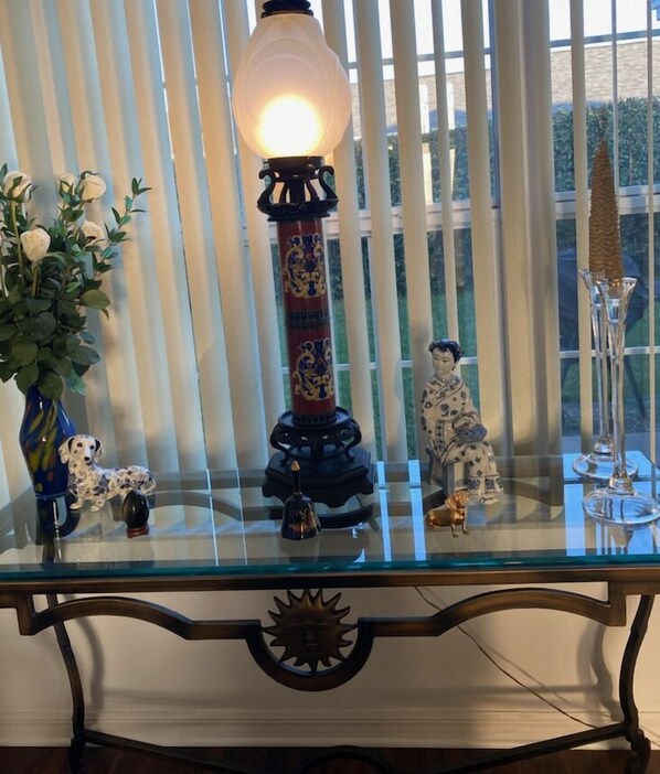 A glass-top table with decorative items including a lamp, figurines, and a vase with flowers.