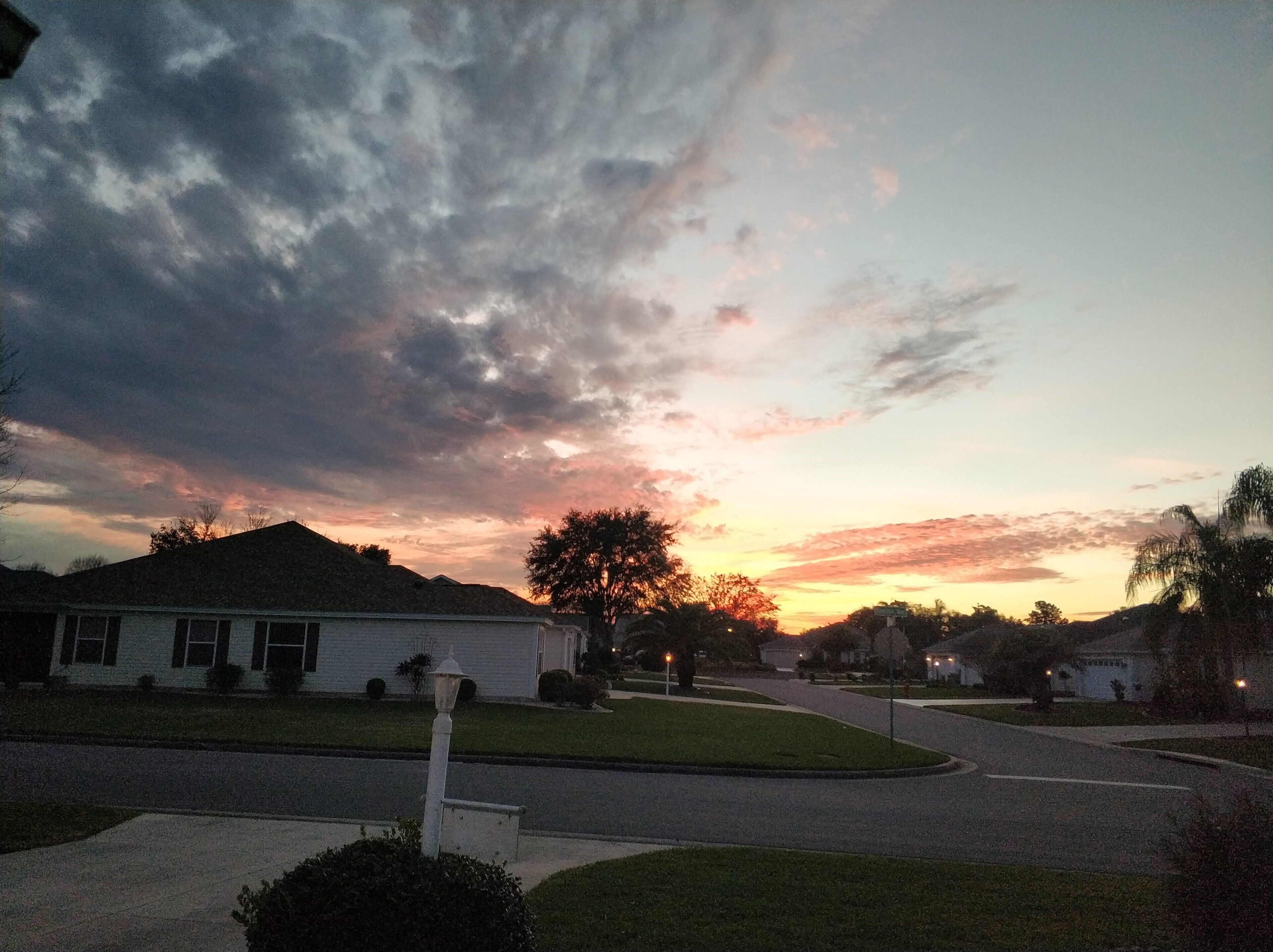 Une rue résidentielle bordée de maisons, un ciel dégagé et un coucher de soleil.
