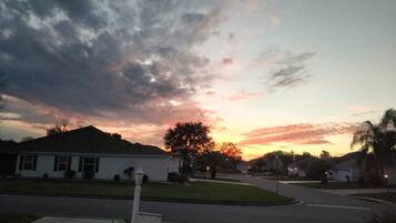 Une rue résidentielle bordée de maisons, un ciel dégagé et un coucher de soleil.