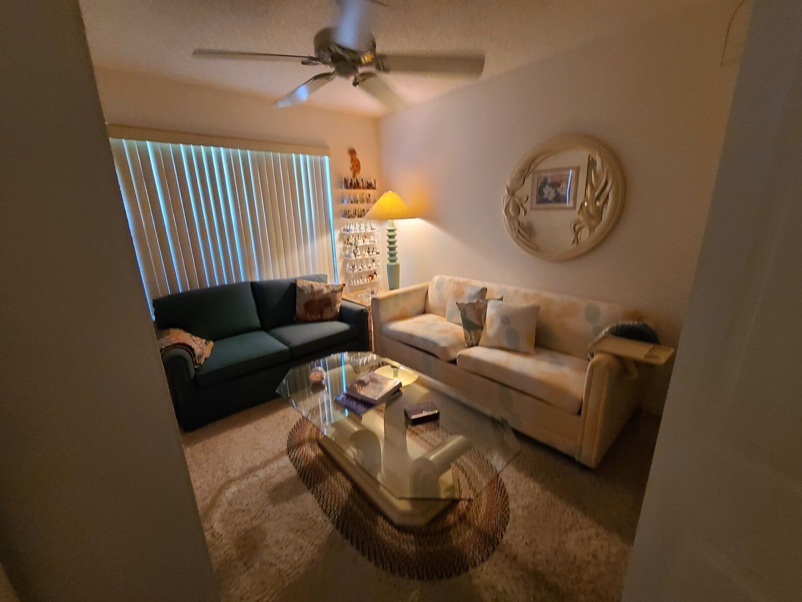 A living room with a ceiling fan, two sofas, a coffee table, and a lamp.