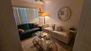 A living room with a ceiling fan, two sofas, a coffee table, and a lamp.