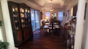 A hallway with a dining area, a cabinet with glass doors, and a chandelier.