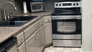 A kitchen with stainless steel appliances, a dishwasher, and a marble-patterned rug. - Quaint, Quiet, and Comfortable Home Away From Home (Hoover)